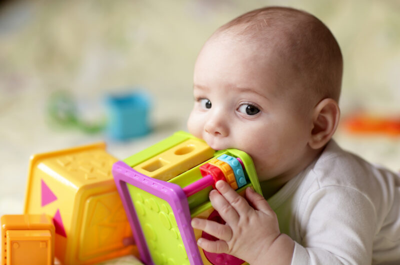 Baby mit Spielzeug im Mund
